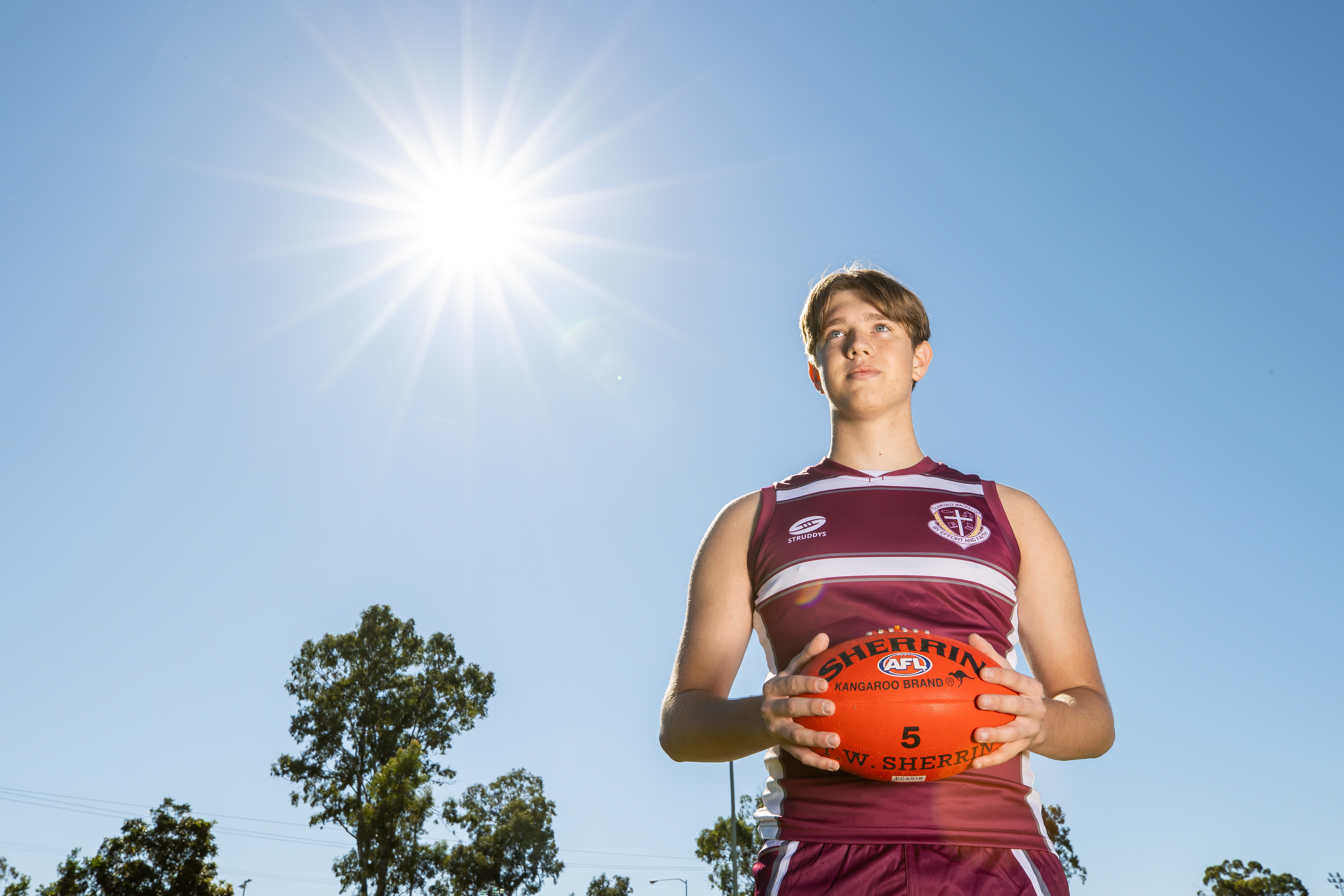 A student is holding an AFL ball.
