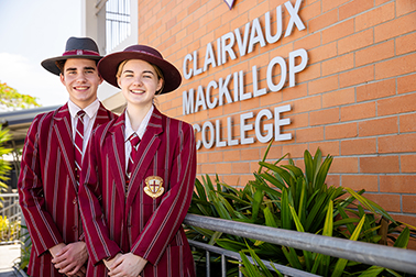 Two students in formal uniform, standing in front of Clairvaux Mackillop College sign.