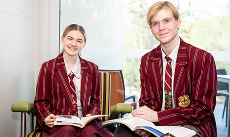 Two students sitting with books and studying.