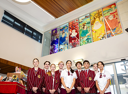 Nine students standing together with their hands crossed in front of them. 