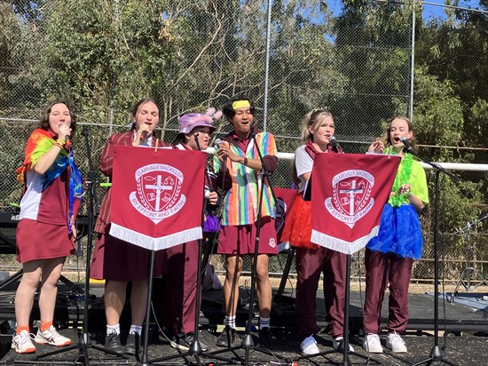 Six students are on a stage and singing.