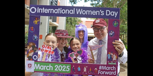 Five people are standing with an International Women's Day frame.