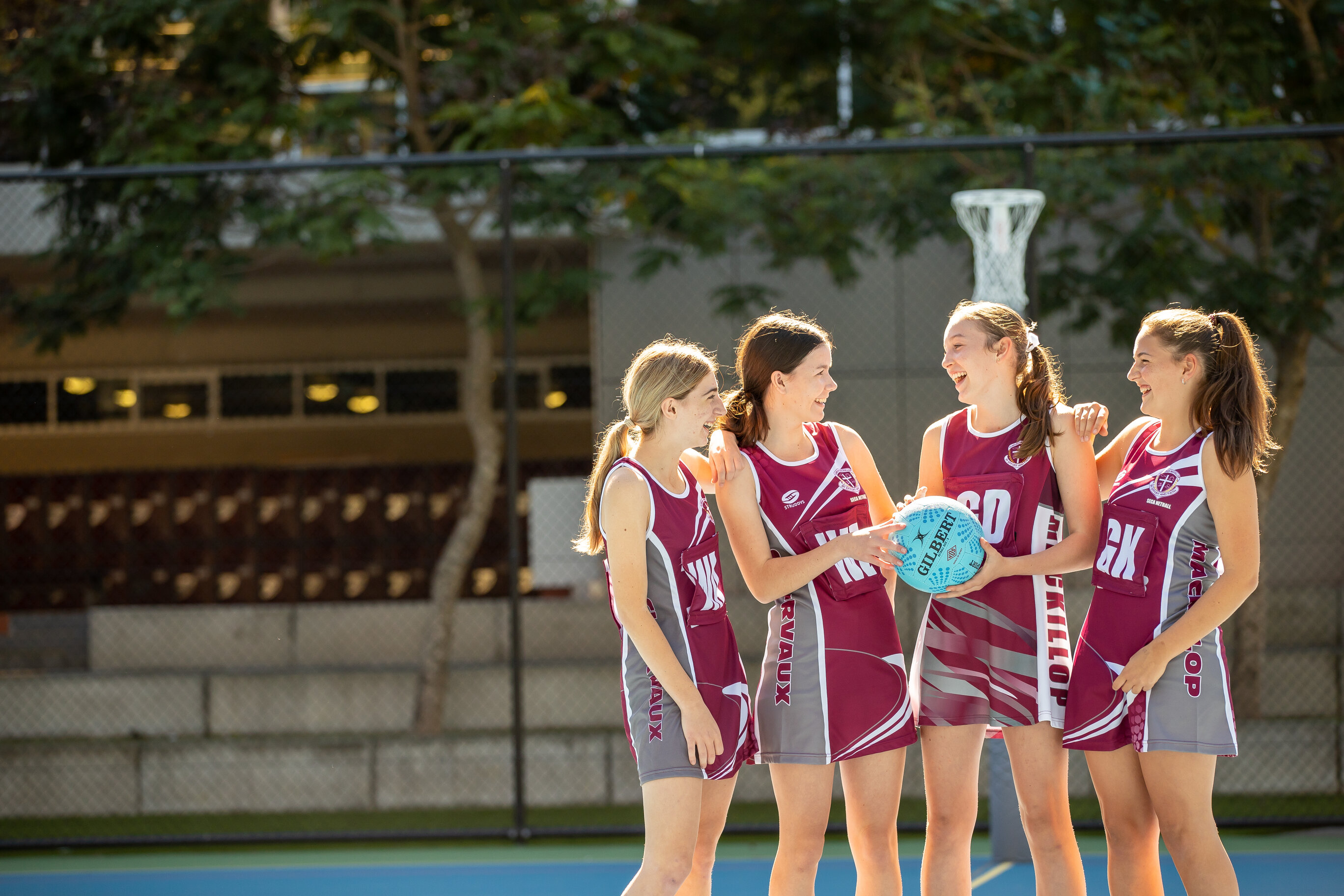 Four netball students standing in a group, laughing.