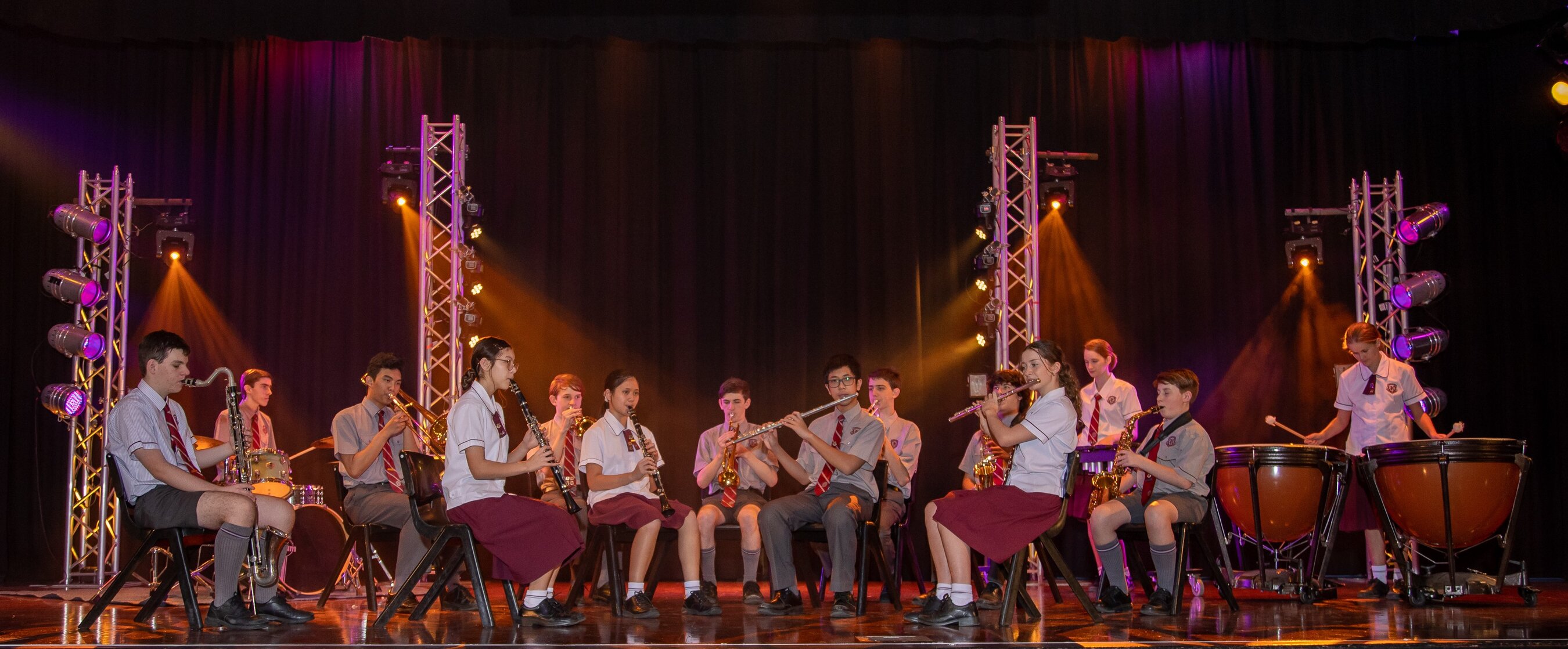 Student orchestra playing on a stage.