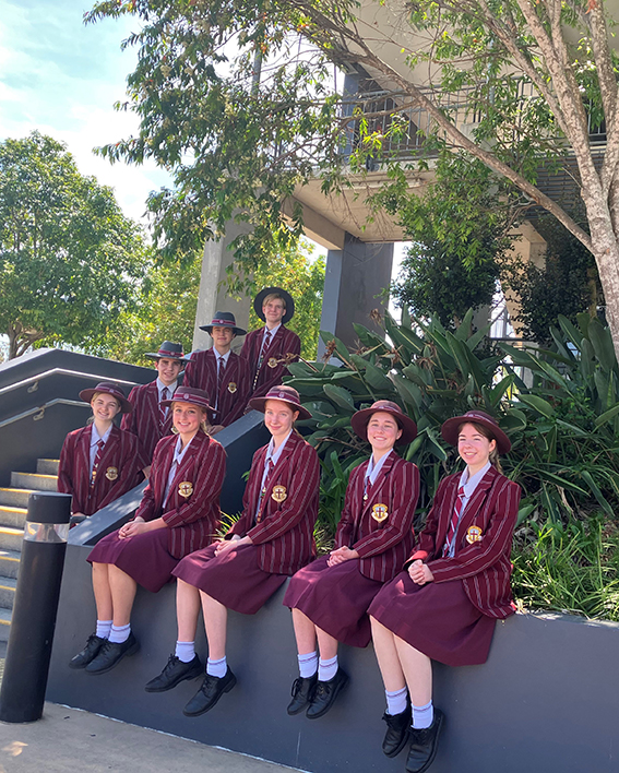 Students at entrance to school. For are seated and four are standing on a step each.